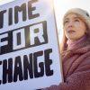 Female Protestor On Demonstration March Holding Time For Change Placard
